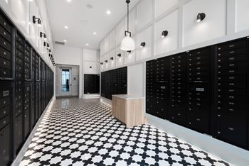 A hallway with black and white checkered flooring and black lockers on the walls.
